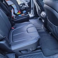 Car interior with rear seat folded up, revealing a wheelchair or mobility lift area in black upholstery.