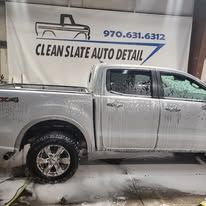 Silver pickup truck being washed in front of a Clean Slate Auto Detail sign.