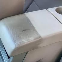 White cushioned armrest with a cup holder, showing a dark stain on the seat.