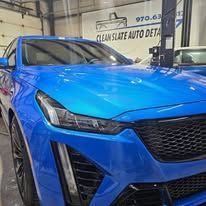 Blue car at an auto detailing shop with a shiny hood and front grille visible