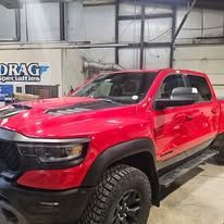 Red pickup truck with black trim parked inside a workshop or garage