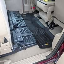 Car interior with black protective floor mats and a folded seat, viewed from the open sliding door