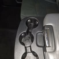 Car cup holder with two drinks and a seat belt buckle beside it