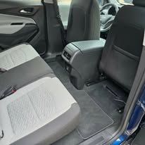 Car rear seat with gray upholstery and folded center armrest, viewed from the open door