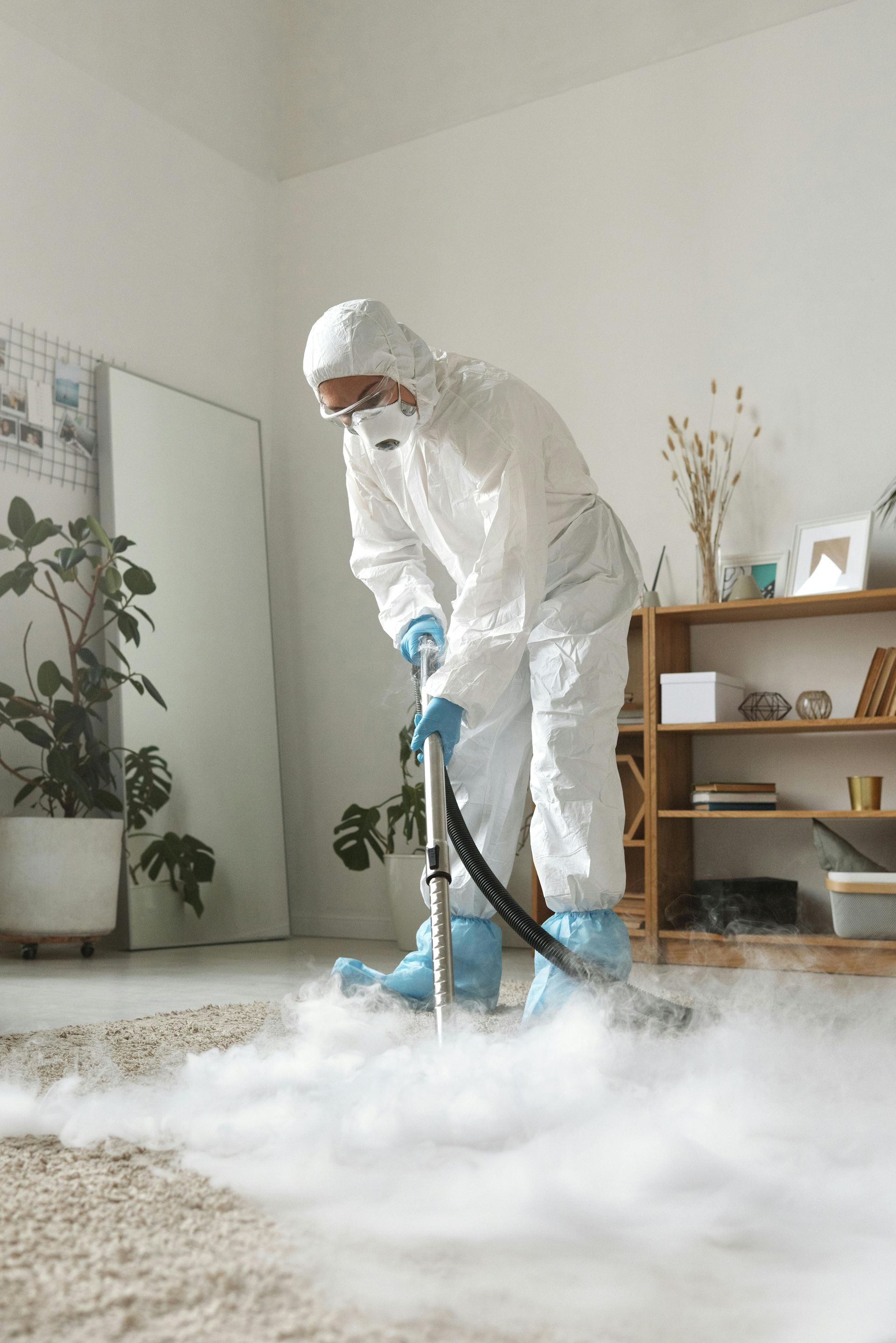 Person in white protective suit vacuuming thick white fog in a living room