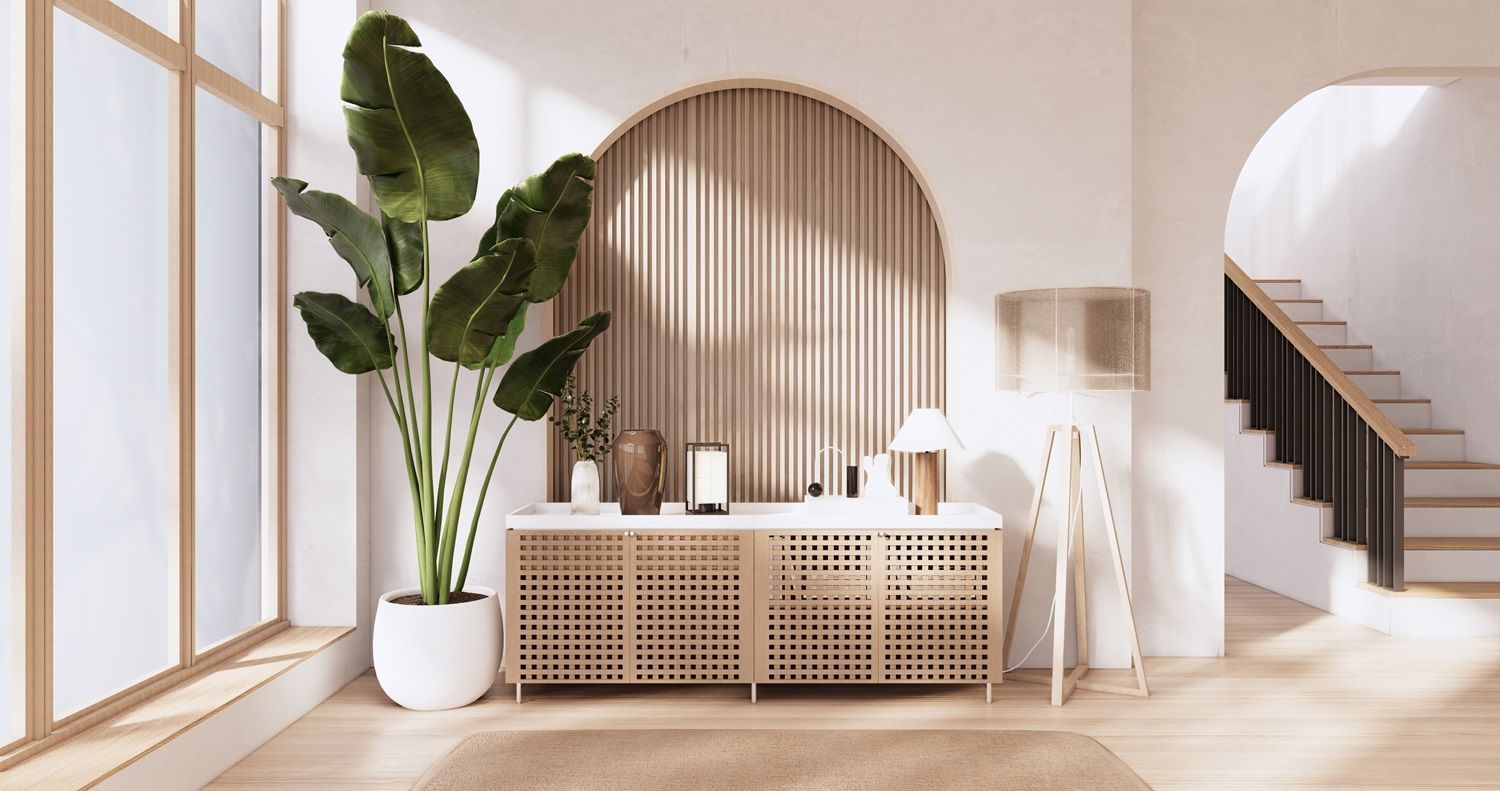 Bright minimalist room with arched mirror, wood cabinet, white decor, and tall potted plant by a window