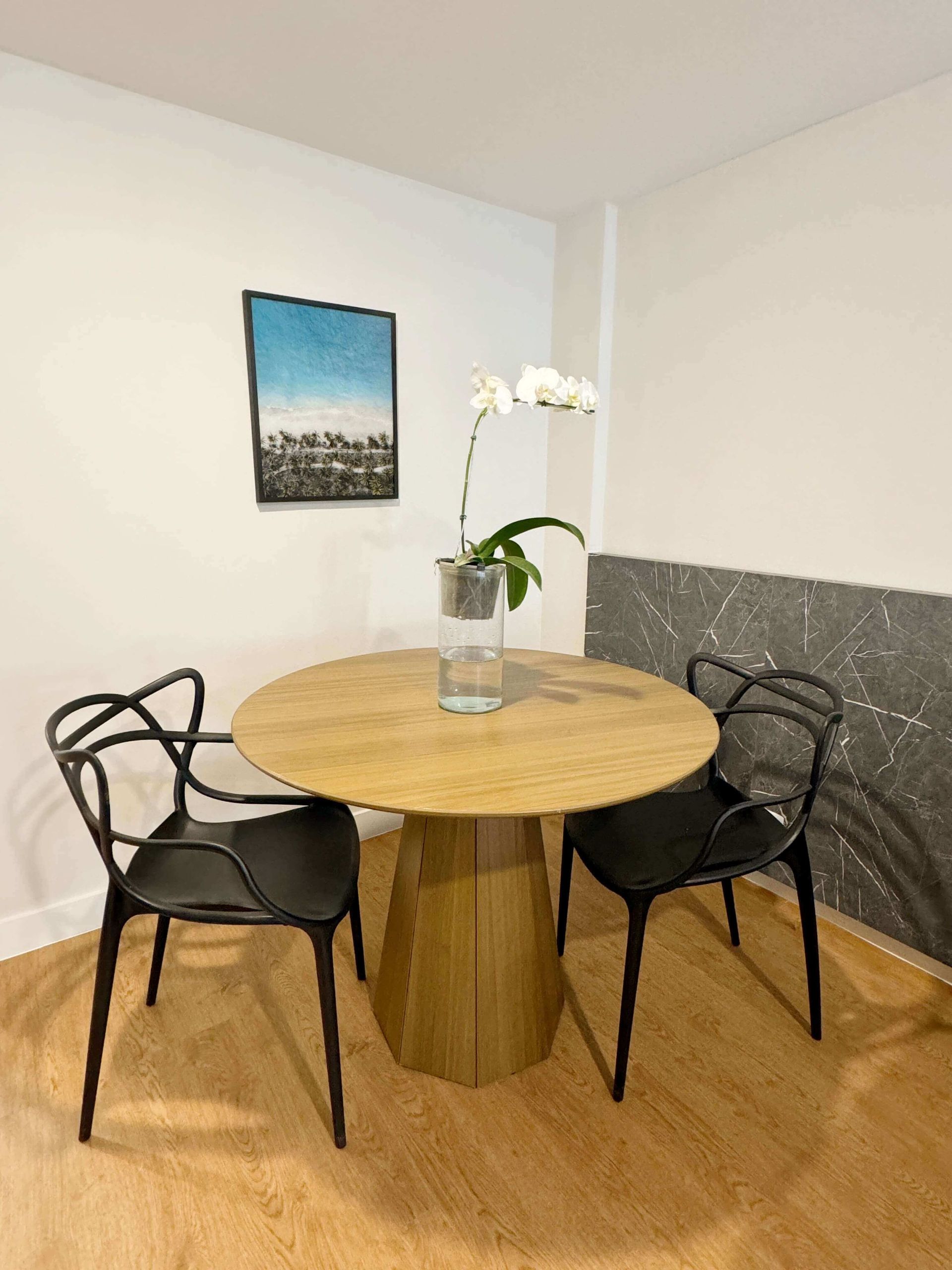 Uma sala de jantar com uma mesa redonda de madeira e cadeiras pretas
