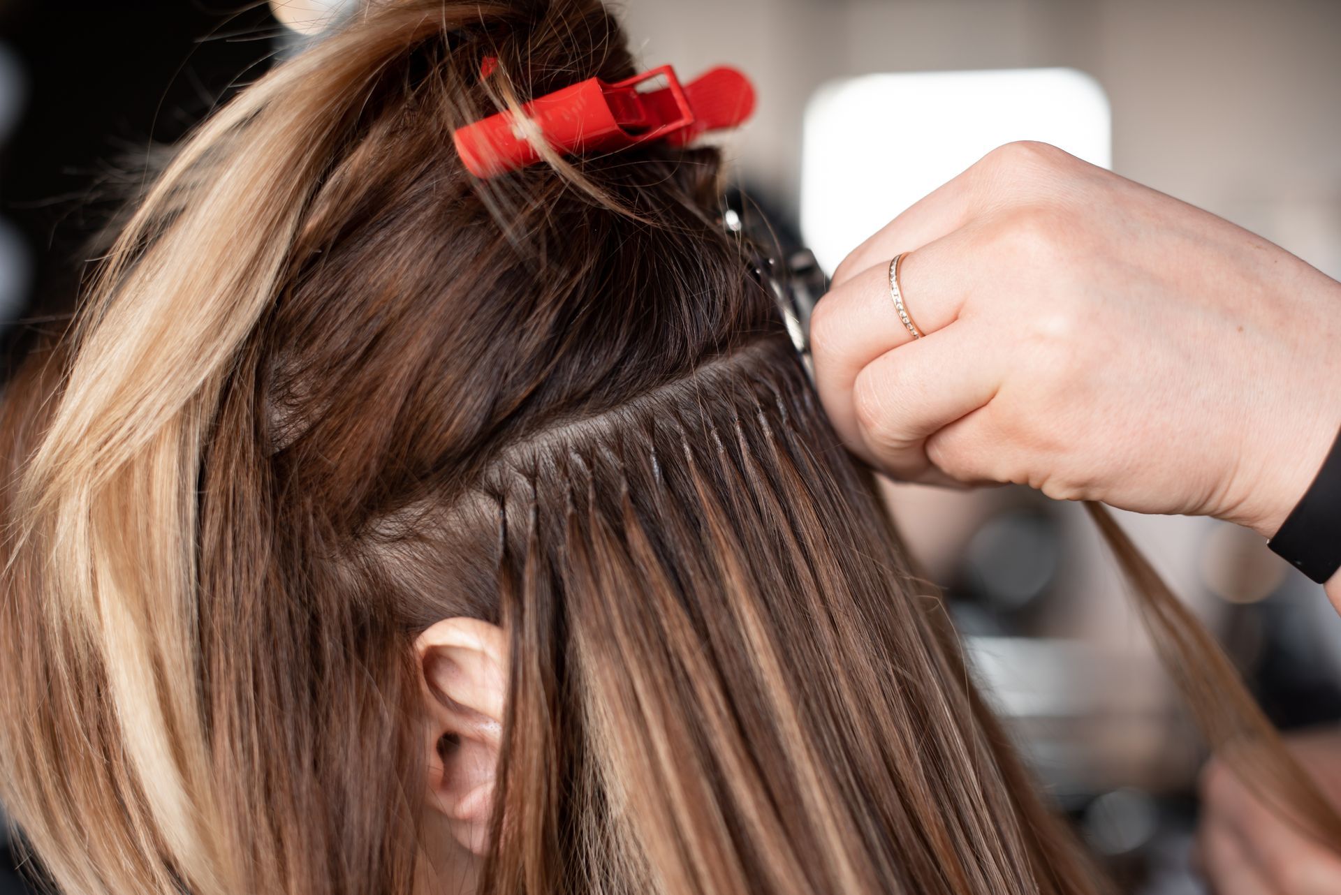 Hair stylist sectioning brown hair with red clips during a salon treatment