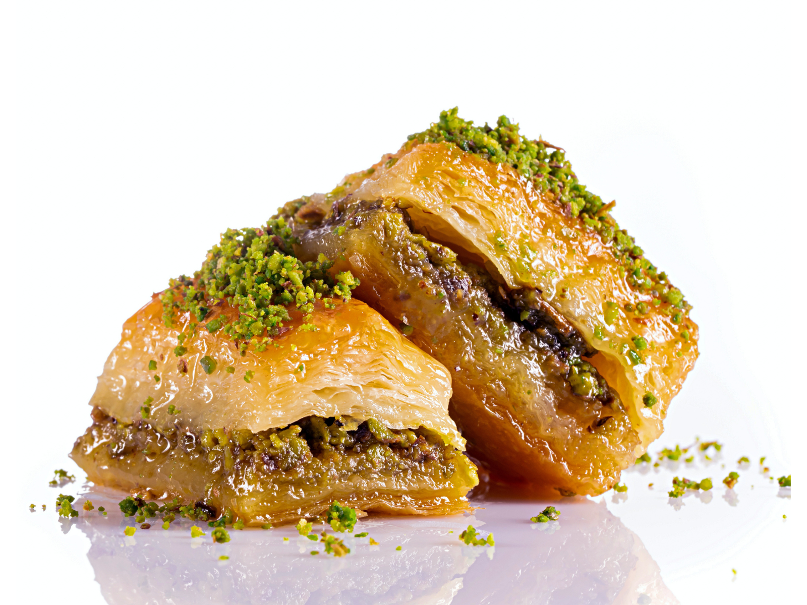 Baklawa Two pieces of baklava with pistachios on top on a white surface.