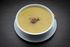 A bowl of soup on a white plate on a table