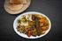 A plate of food with rice , meat , vegetables and hummus on a table.