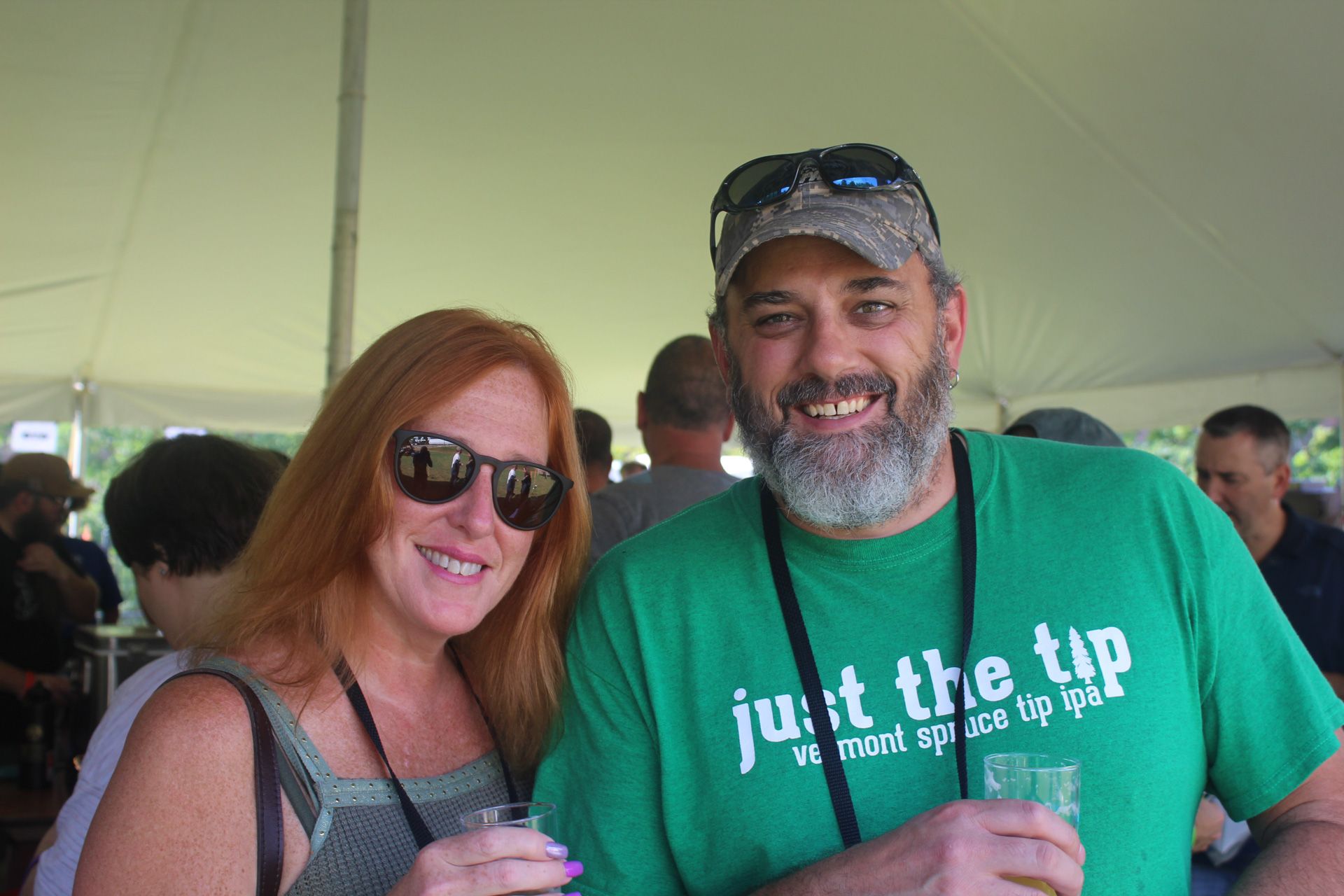A man and a woman are posing for a picture and the man is wearing a green shirt that says just the tip.