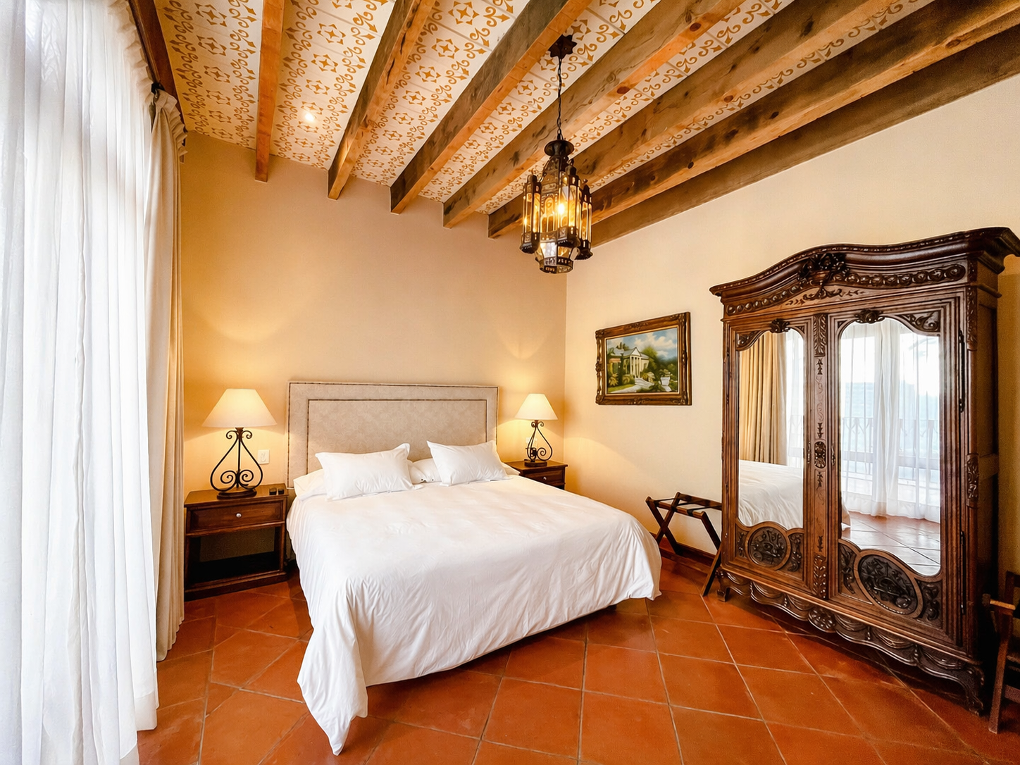 Una habitación de hotel amueblada con una cama de matrimonio, vigas de madera en el techo, suelos de baldosas de terracota y un gran armario.