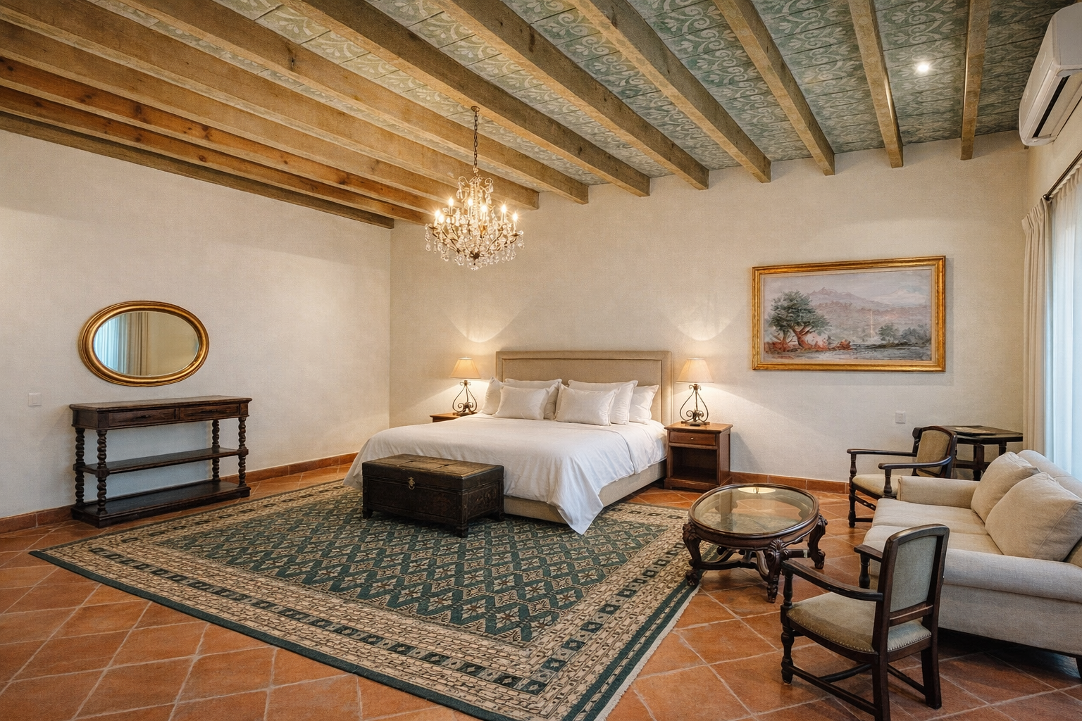 Un dormitorio amplio y rústico cuenta con una cama king size, techo con vigas de madera, lámpara de araña, zona de estar y una alfombra estampada.