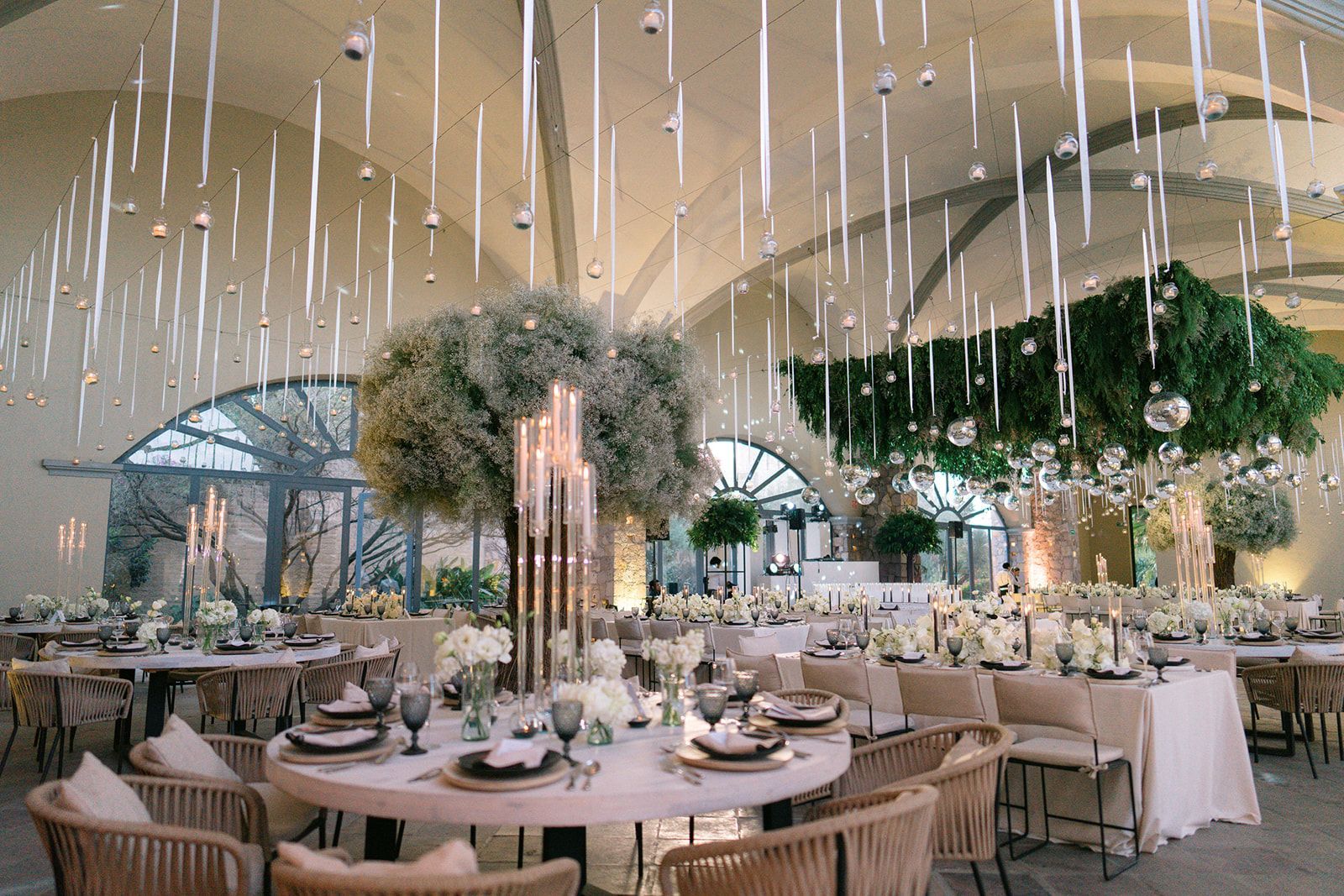 Recepción de boda bajo árboles con decoración colgante en Hacienda Los Arcángeles