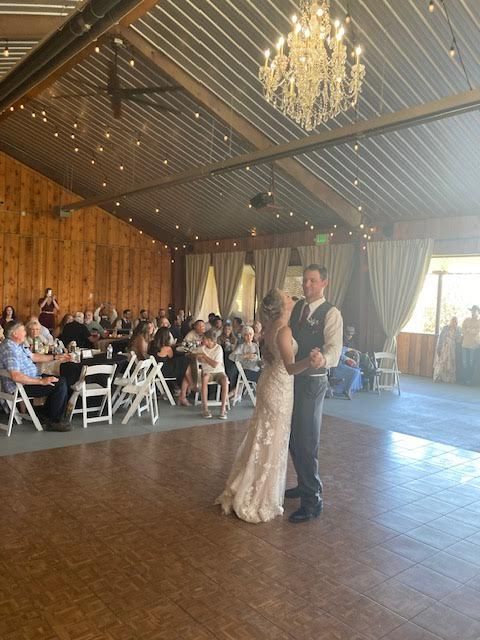 A bride and groom are dancing in front of a crowd at their wedding reception.