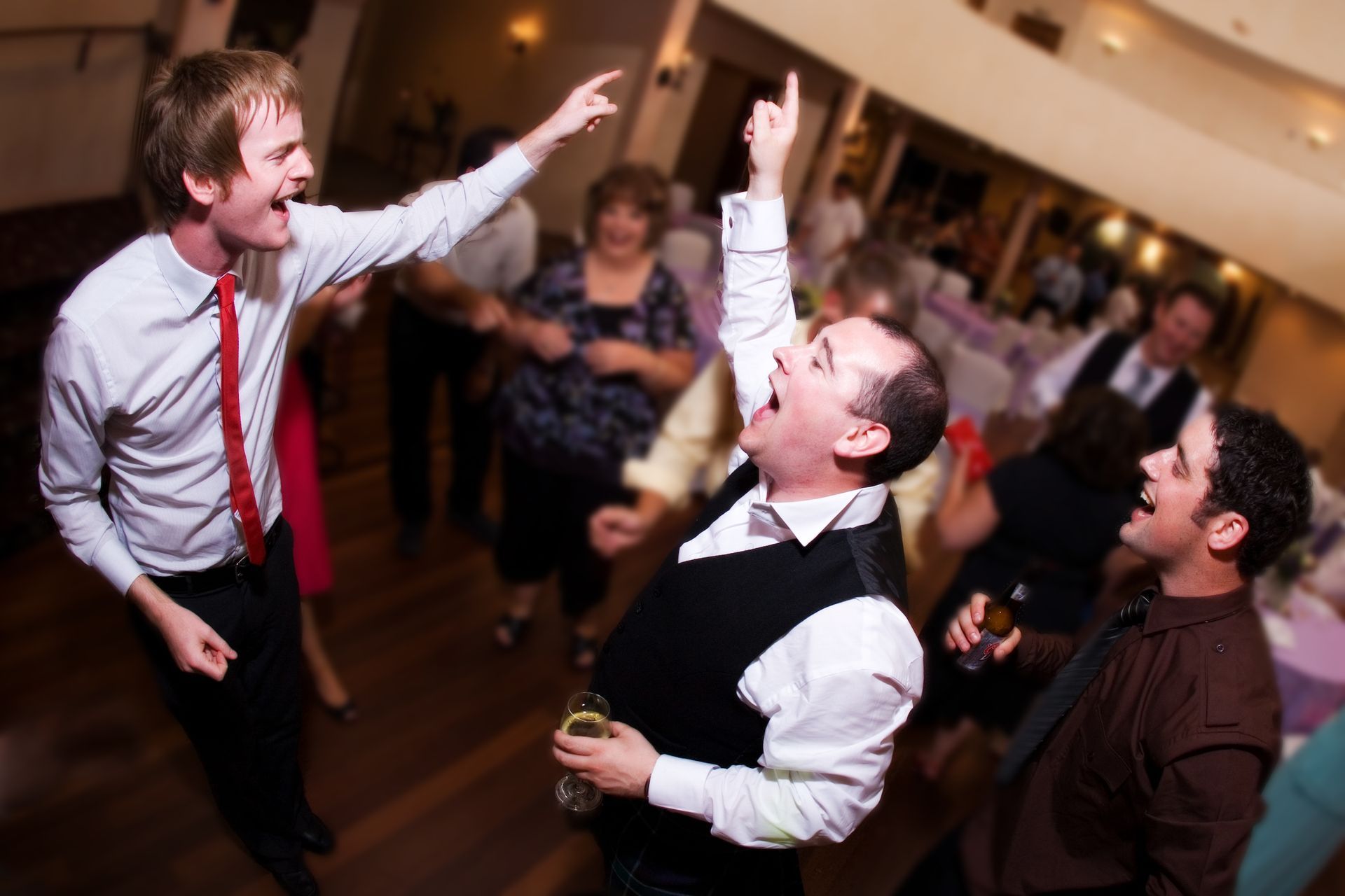 A group of people are dancing in a room and one man is pointing at another man.