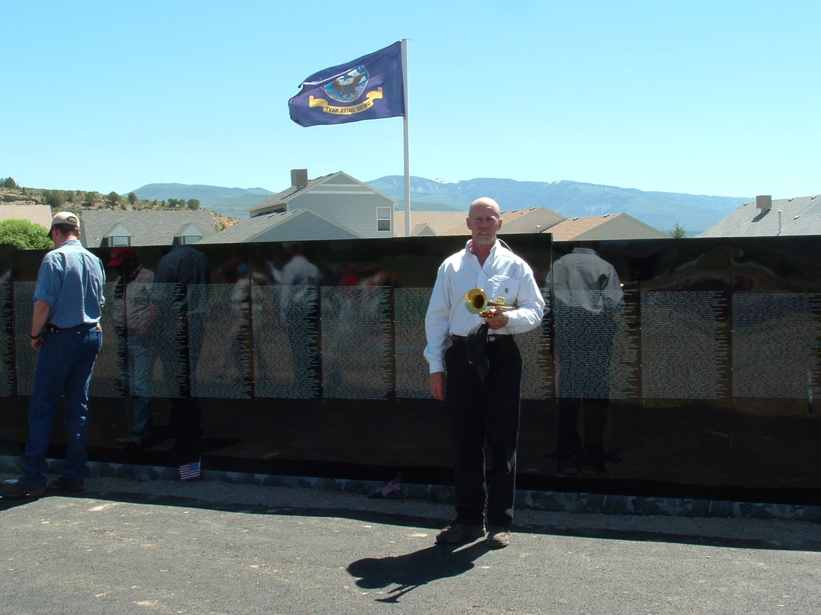 A man stands in front of a wall with a flag in the background