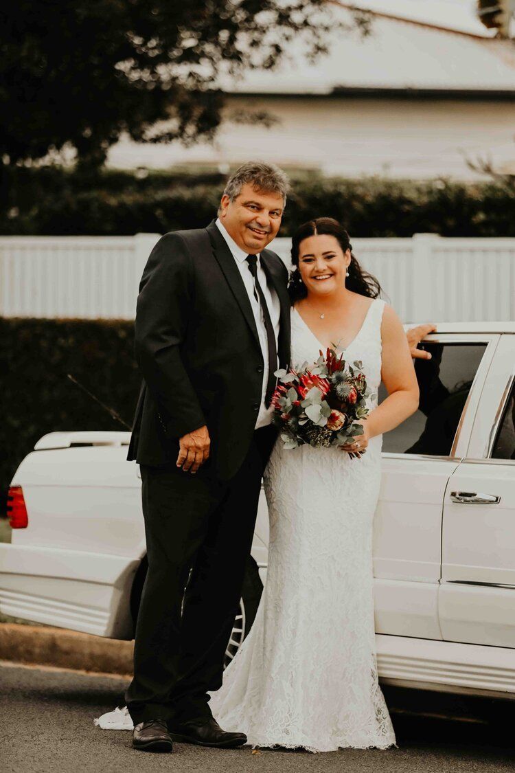 Happy Bride and Groom In Front Of Limo — Classic Car Hire in Dundowran Beach, QLD