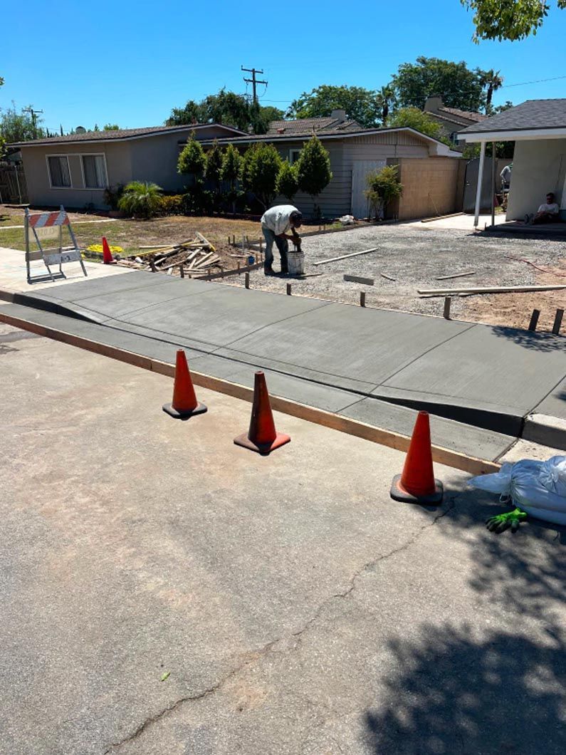A man is working on a concrete driveway in front of a house.