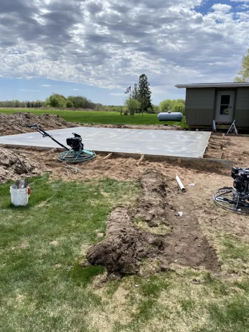 Backyard construction site with a partially installed pond liner, dirt pile, and a small shed nearby