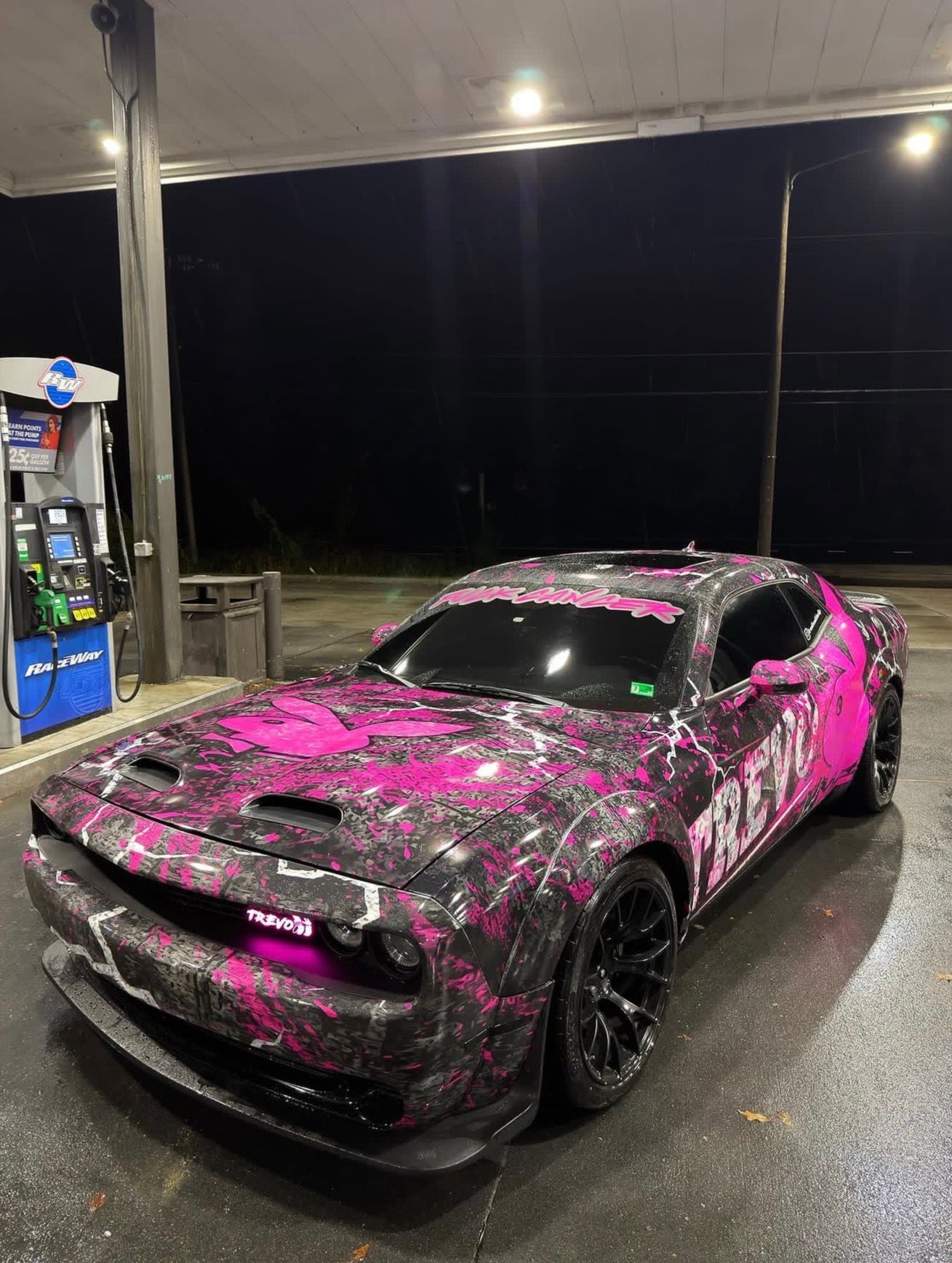 Pink-and-black sports car at a gas station at night