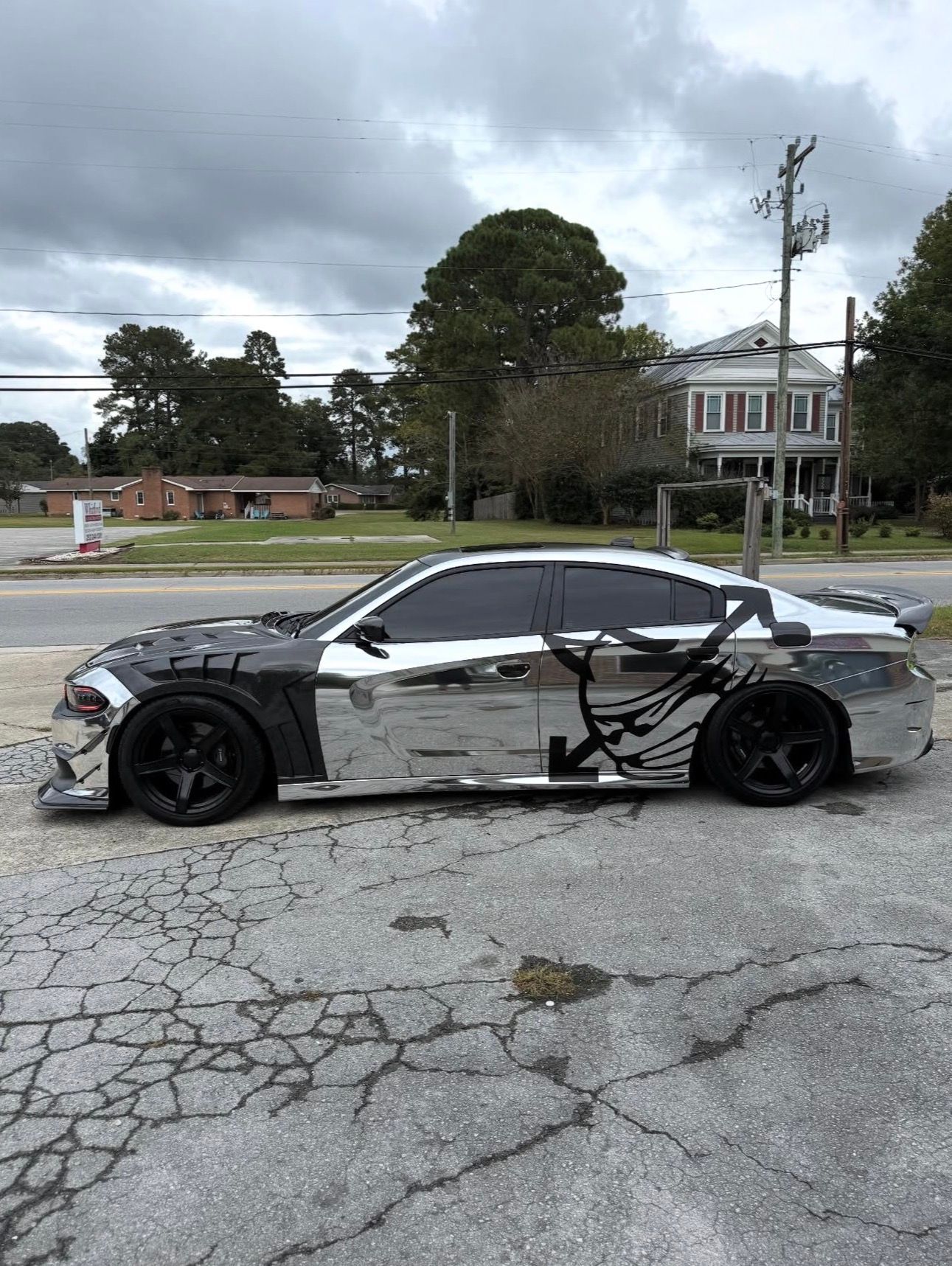 chrome sports car parked on a cracked street under cloudy skies