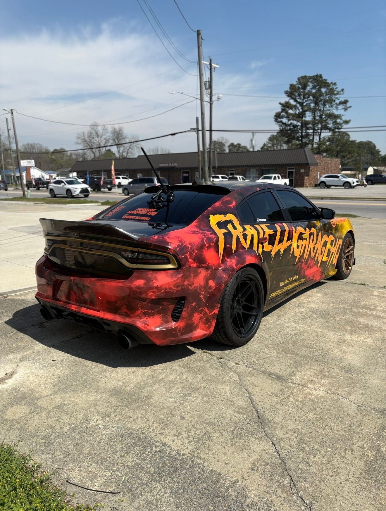 Red-and-black custom sports car with graffiti-style yellow lettering parked outdoors on pavement.