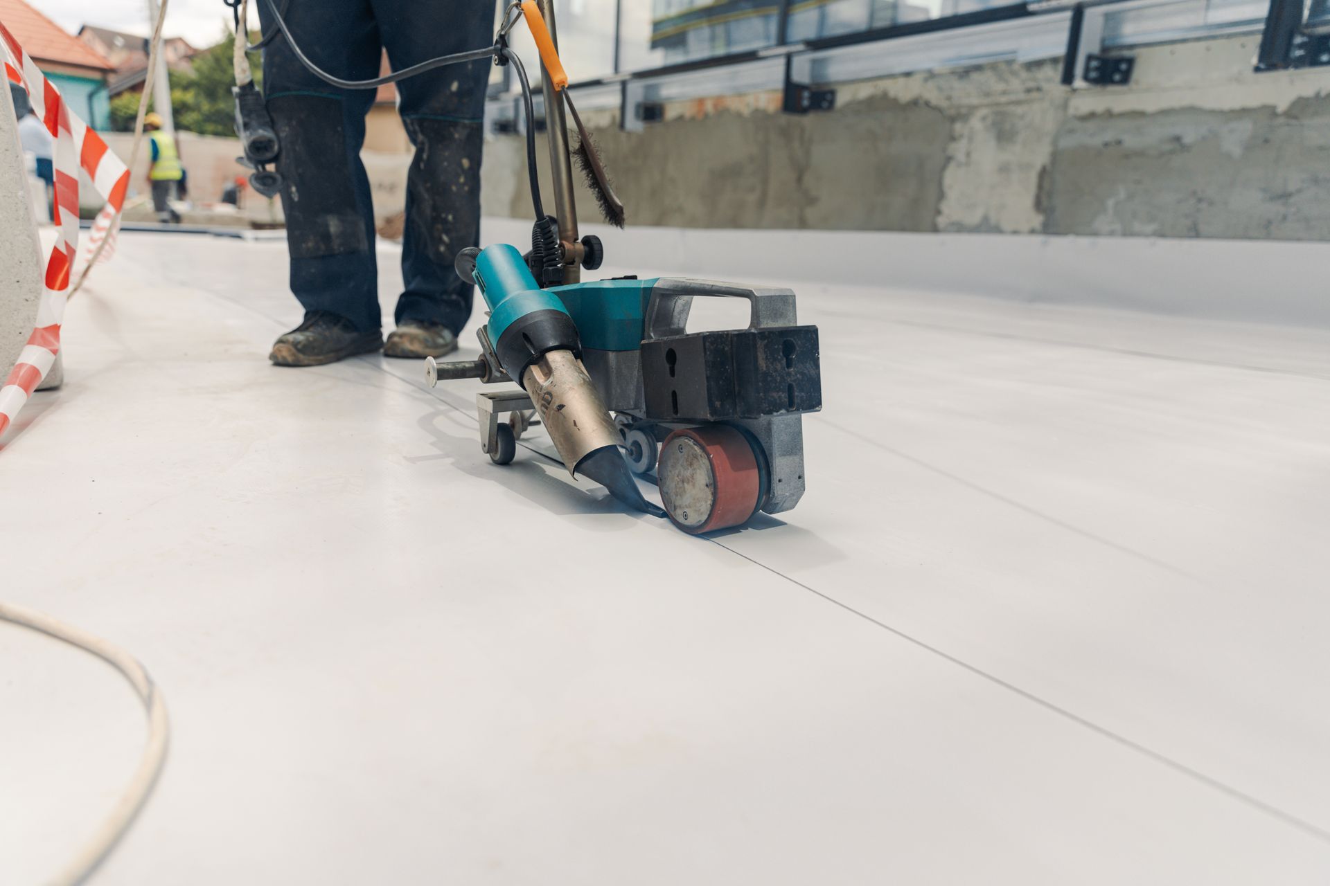 Roofer heat-welding a PVC membrane seam on a commercial flat roof