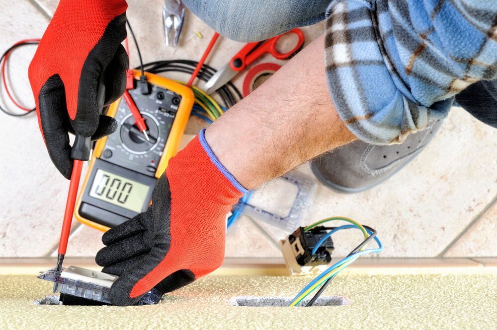 Electrician Uses a Multimeter on Wires in a Wall — Quaite Electrical Pty Ltd In Bundaberg, QLD