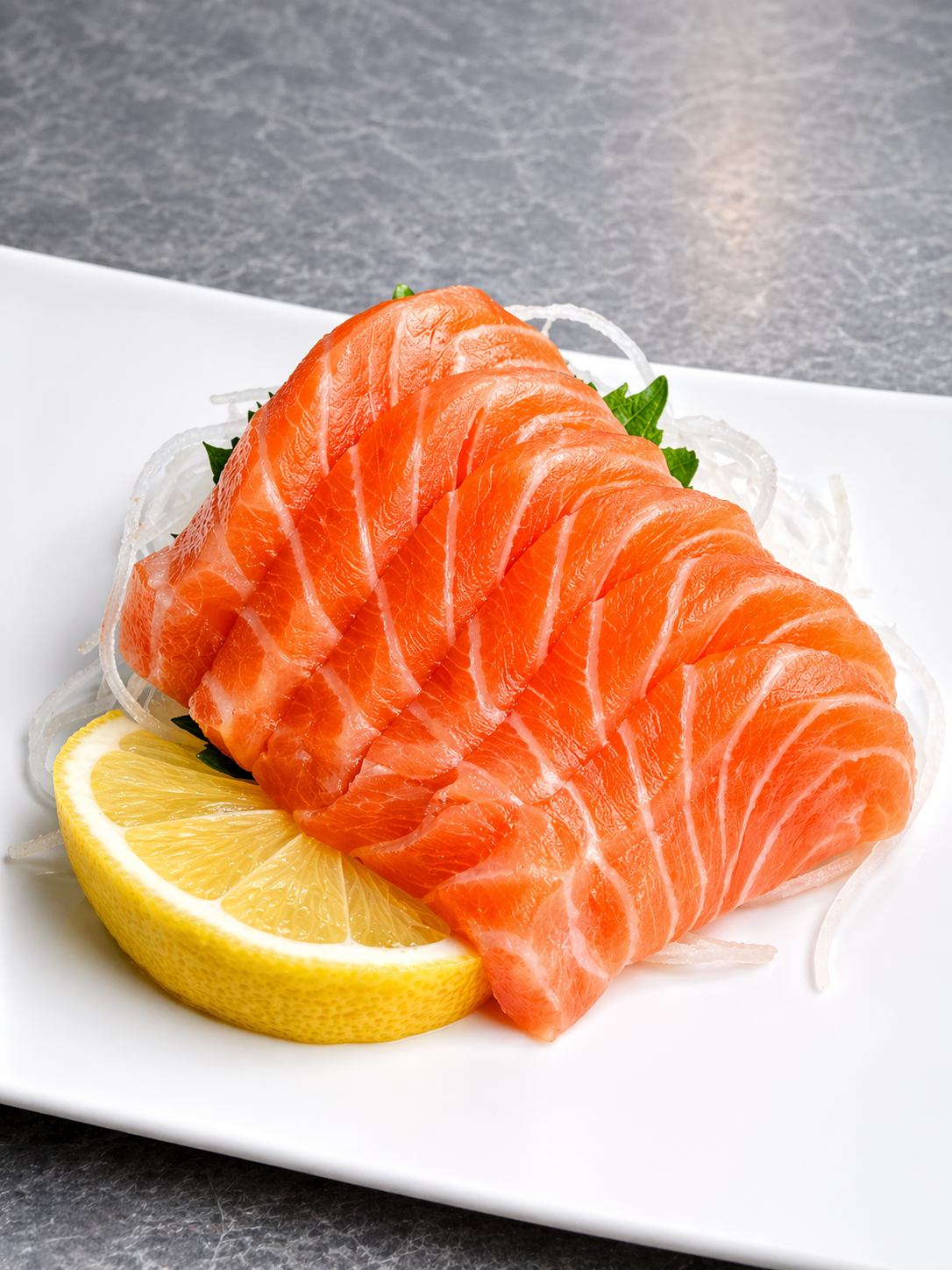 Slices of raw salmon sashimi with a lemon wedge on a white plate