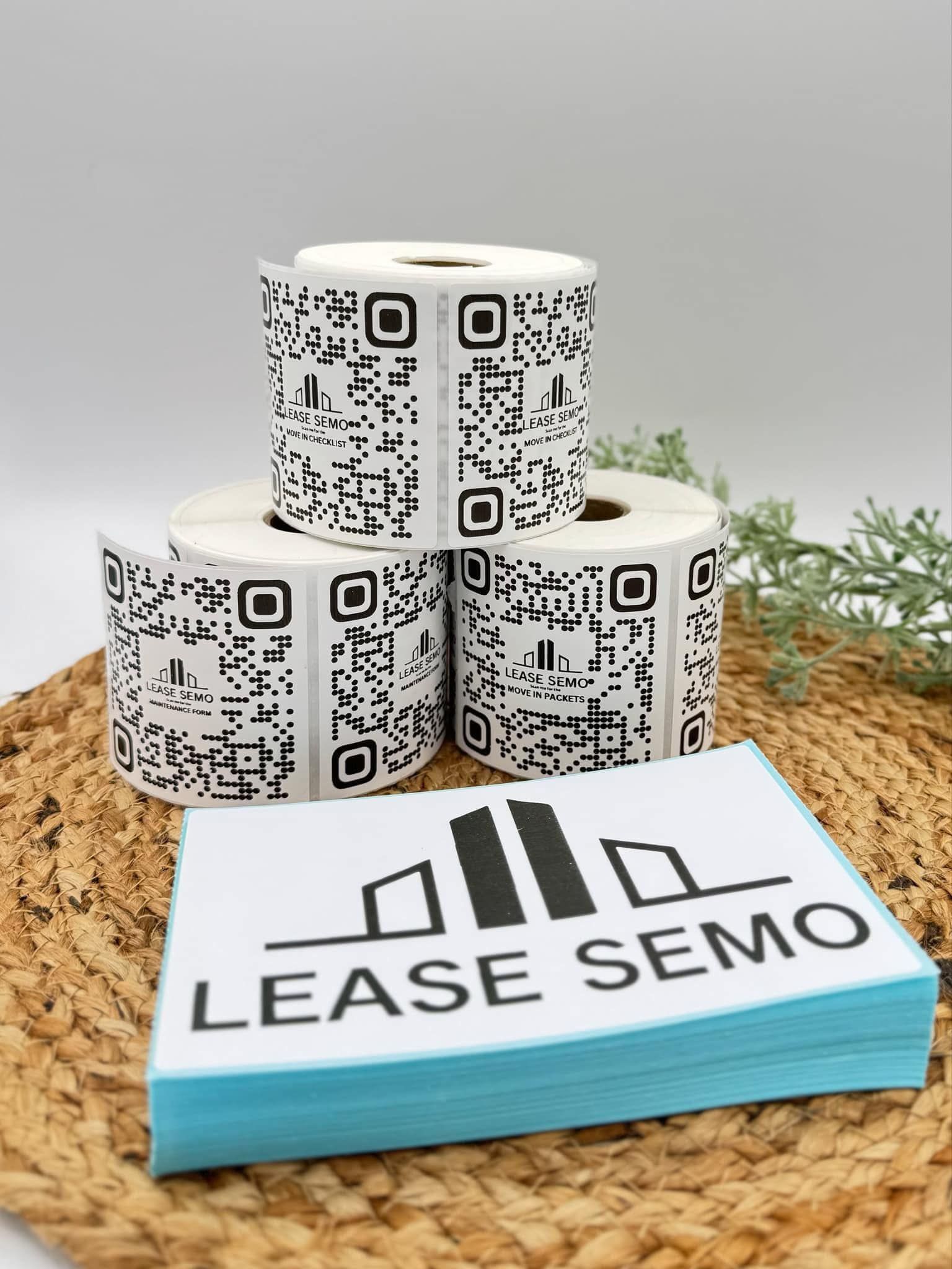 Rolls of QR code labels stacked with a stack of