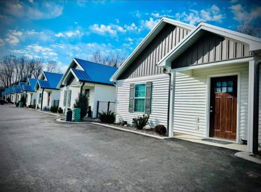Row of white cottages with blue roofs, brown doors, and a paved walkway under a blue sky.