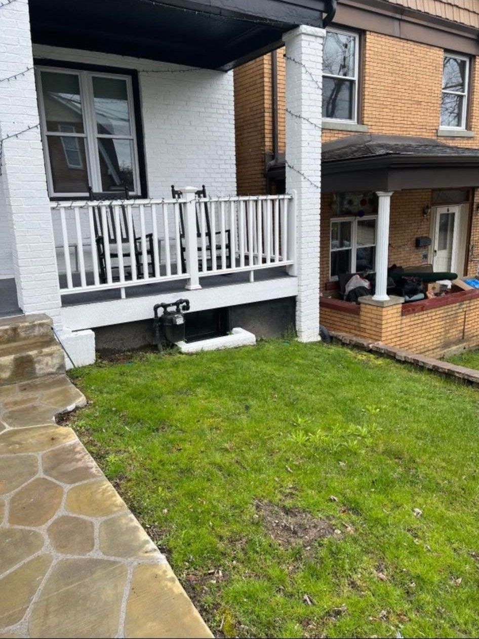 Apartment building exterior with tree, shrubs, and empty paved street in front