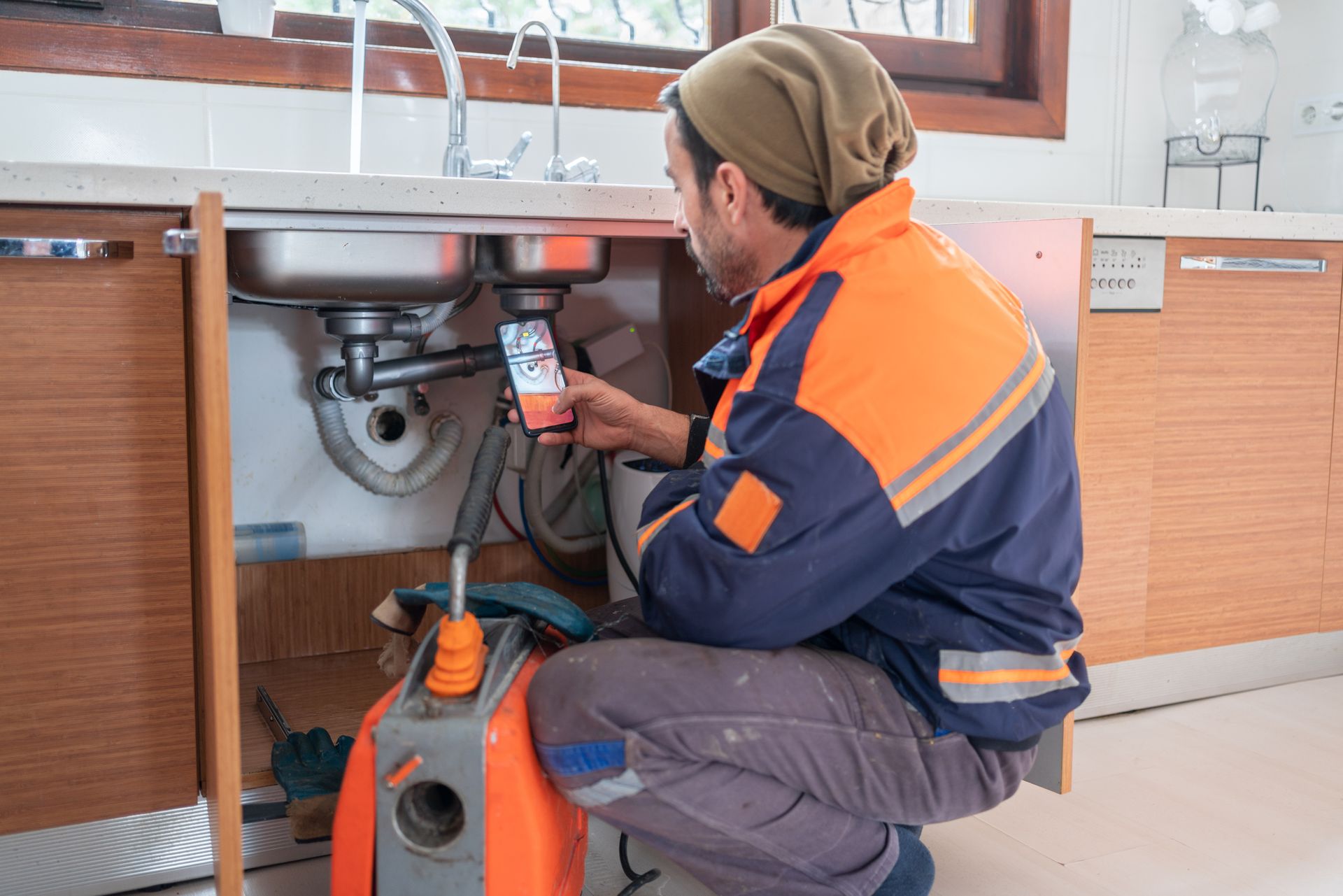 A plumber is fixing a sink in a kitchen.