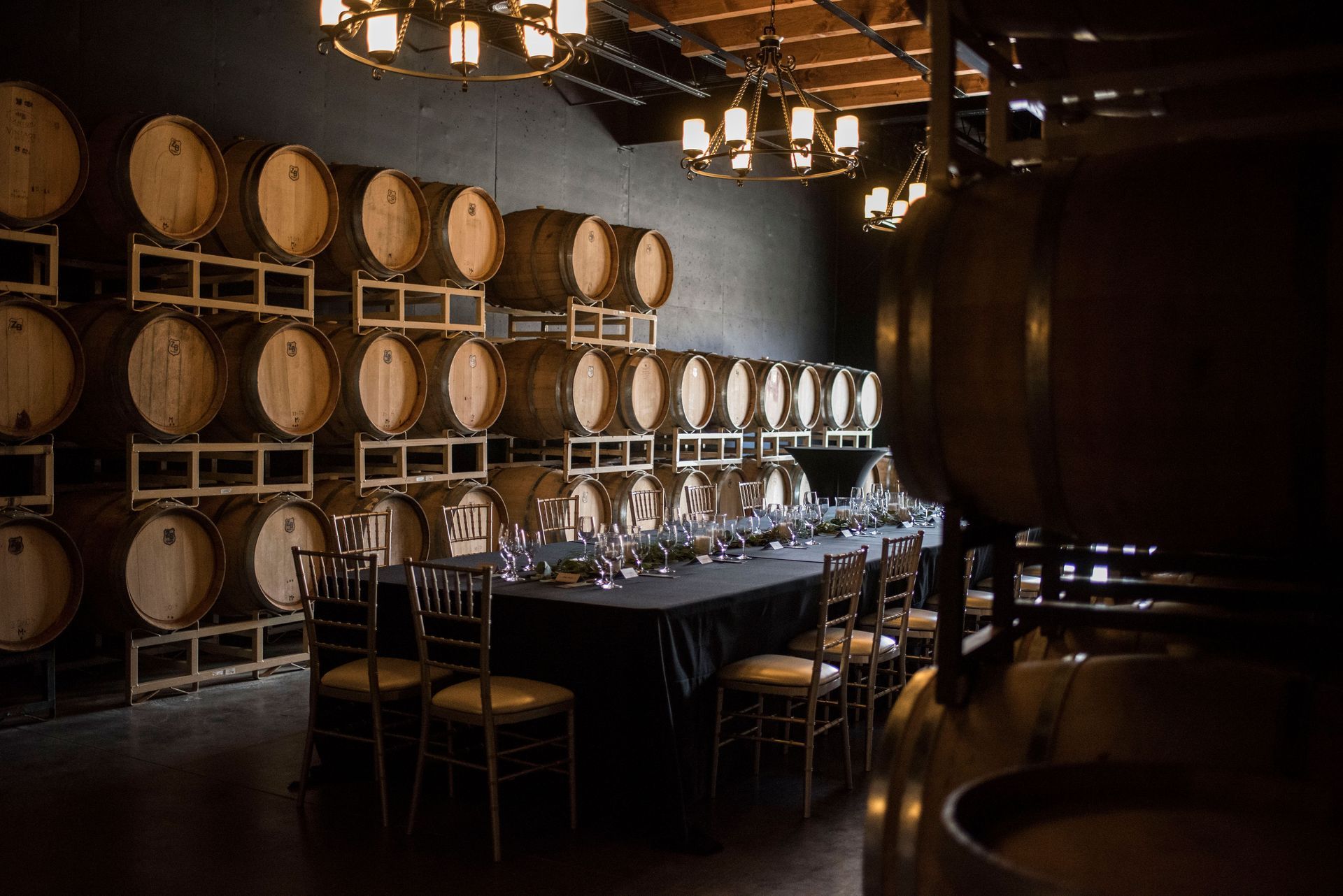 A long table in a wine cellar surrounded by barrels