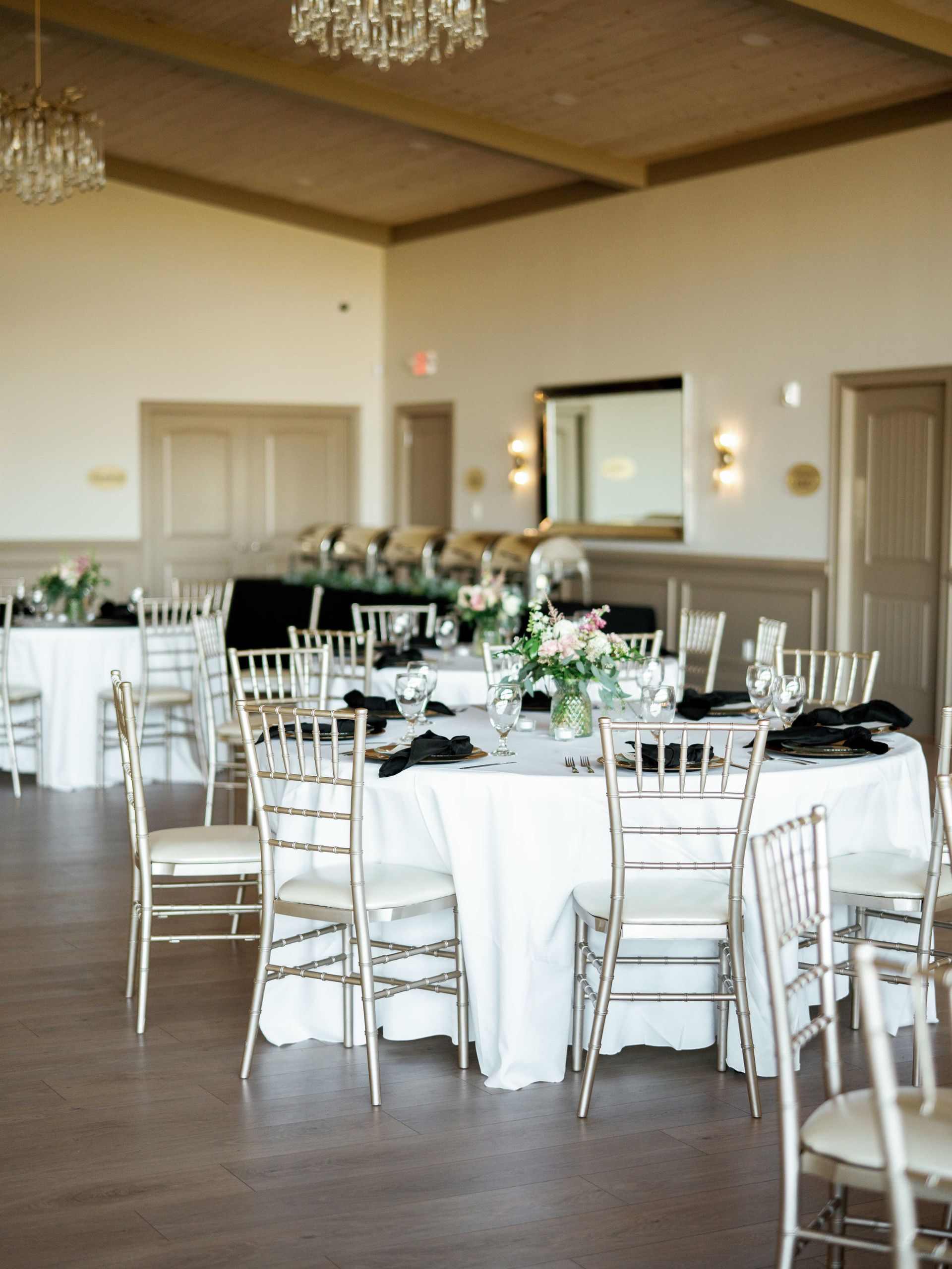 A large room with tables and chairs set up for a wedding reception