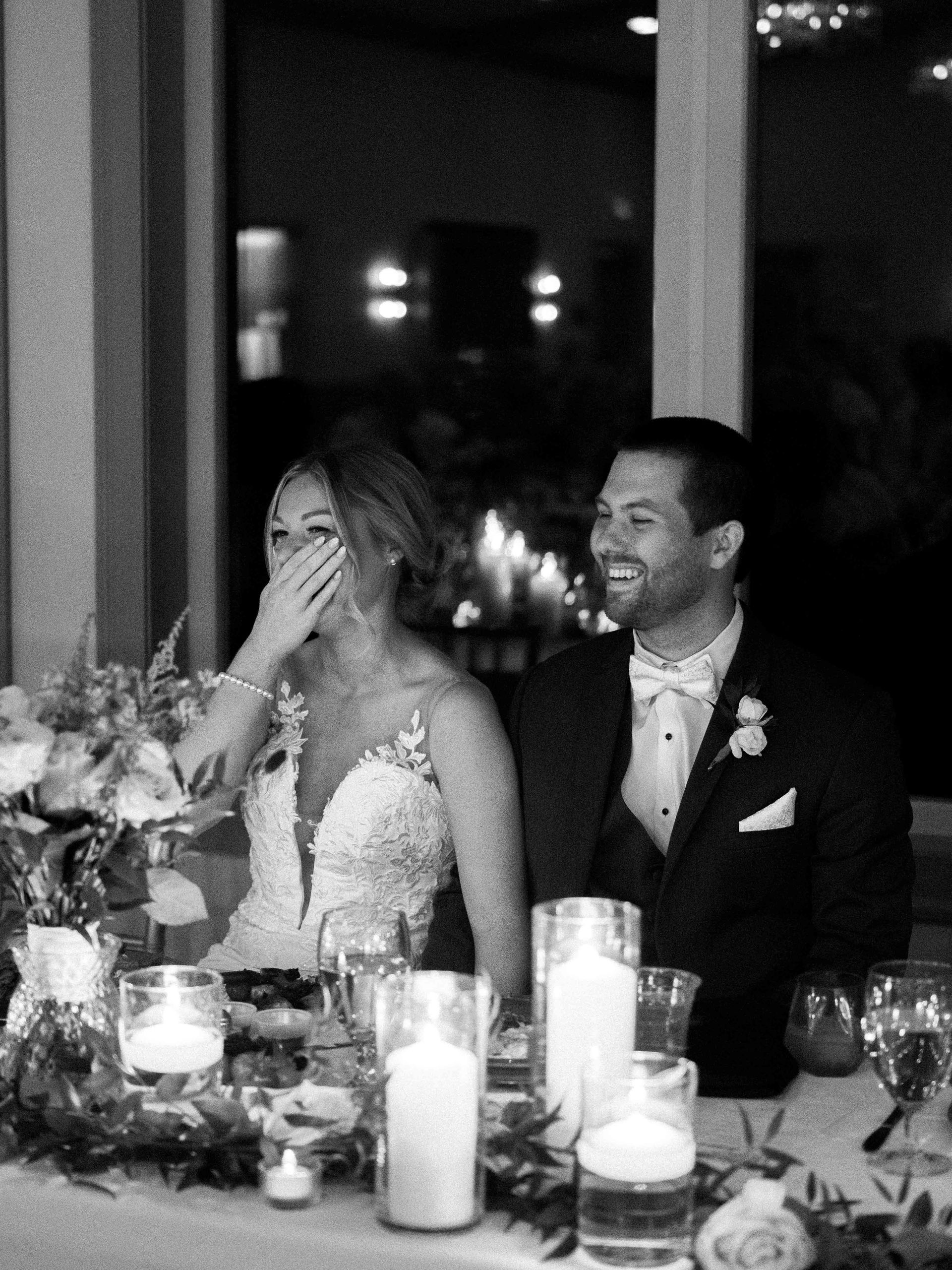 A bride and groom are sitting at a table with candles.