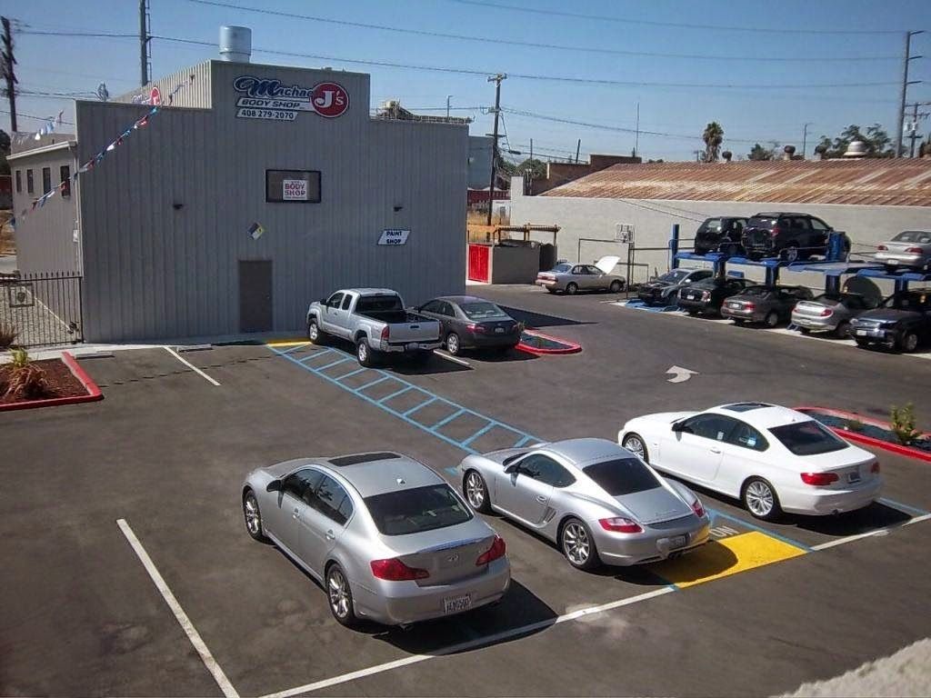 Cars parked at a garage with a gray building, blue skies and sunny weather.