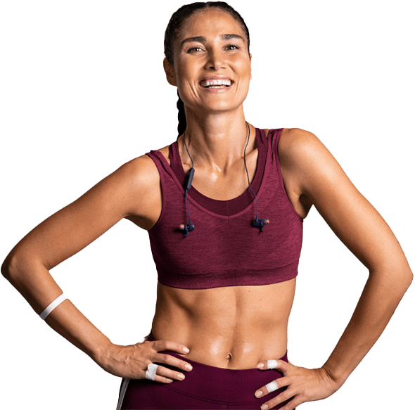 Smiling athlete in maroon sportswear with hands on hips, wearing earbuds against a white background