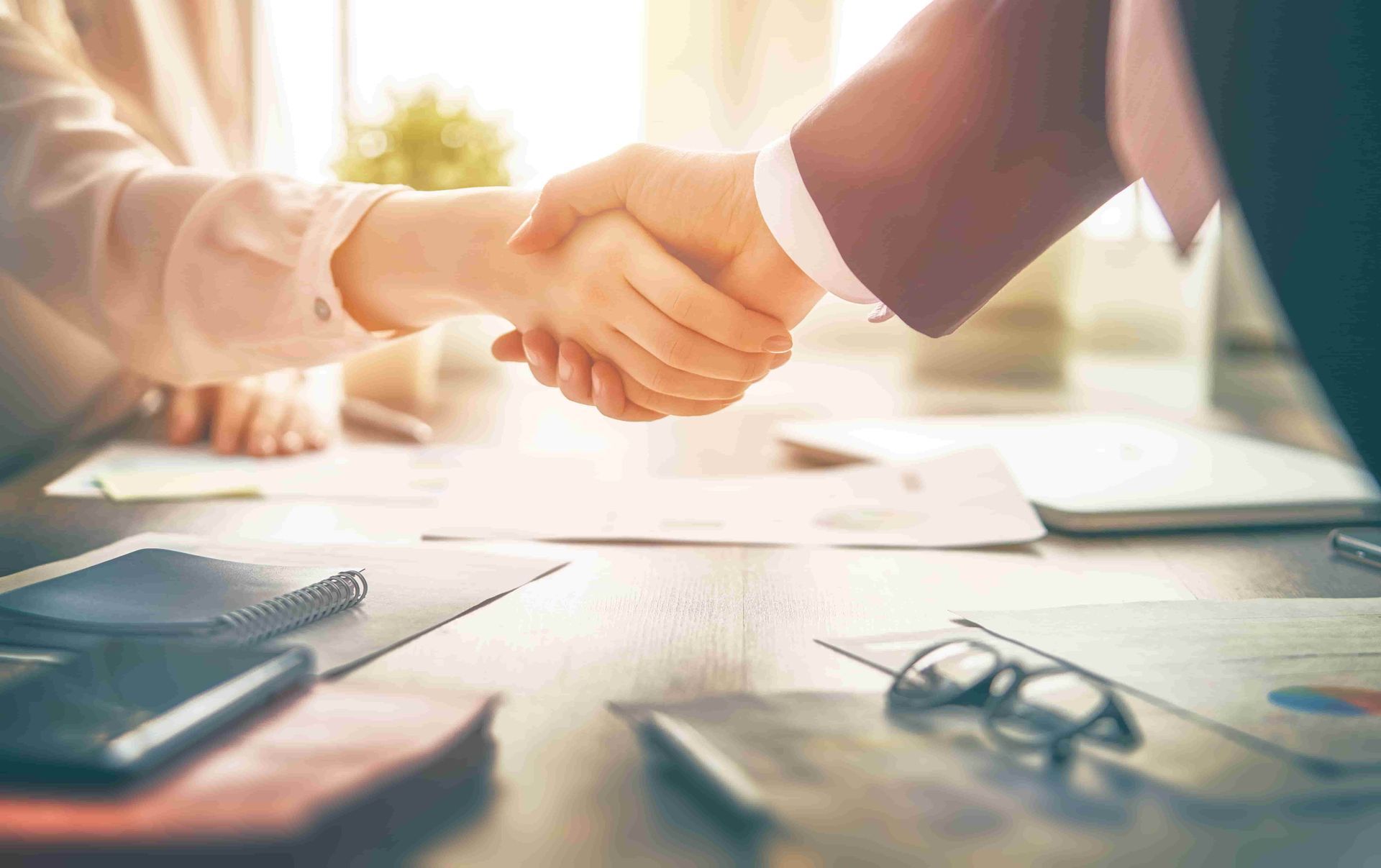 Two people are shaking hands over a table — Jennifer O'Shea Bookkeeping & BAS Agent in Miami, QLD