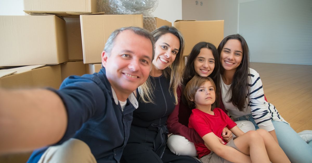 Una familia se toma una selfie en un sofá con cajas de mudanza de fondo.