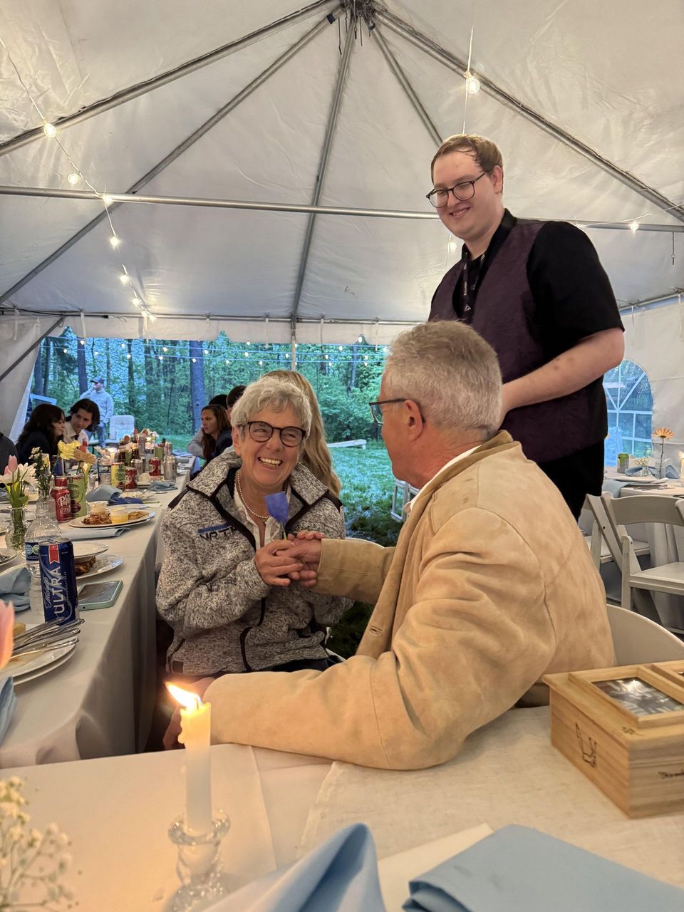 Sidney Lee performing close-up magic for guests at a tented wedding reception