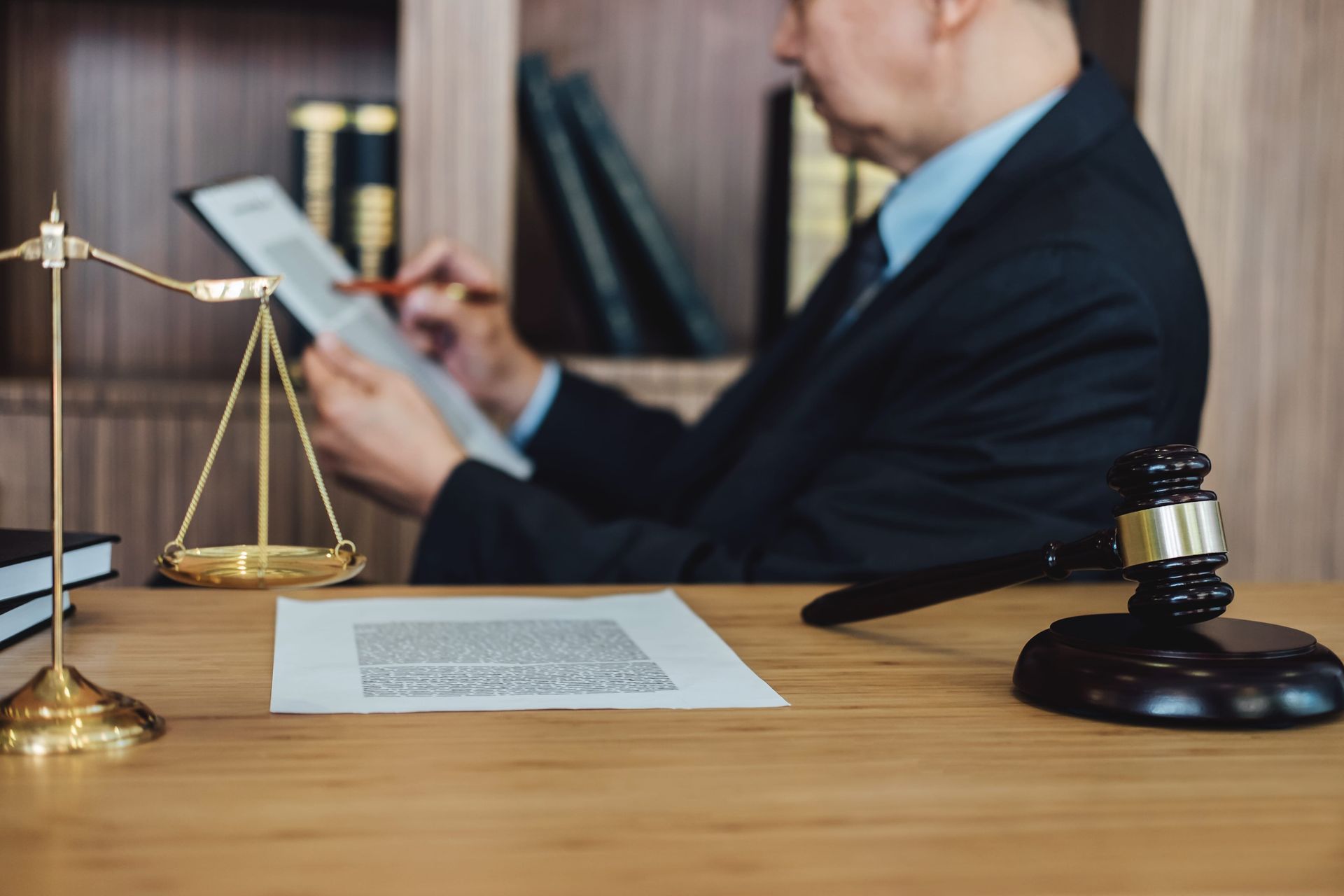 Attorney reviewing documents at a desk with a balance scale and judge’s gavel in a law office
