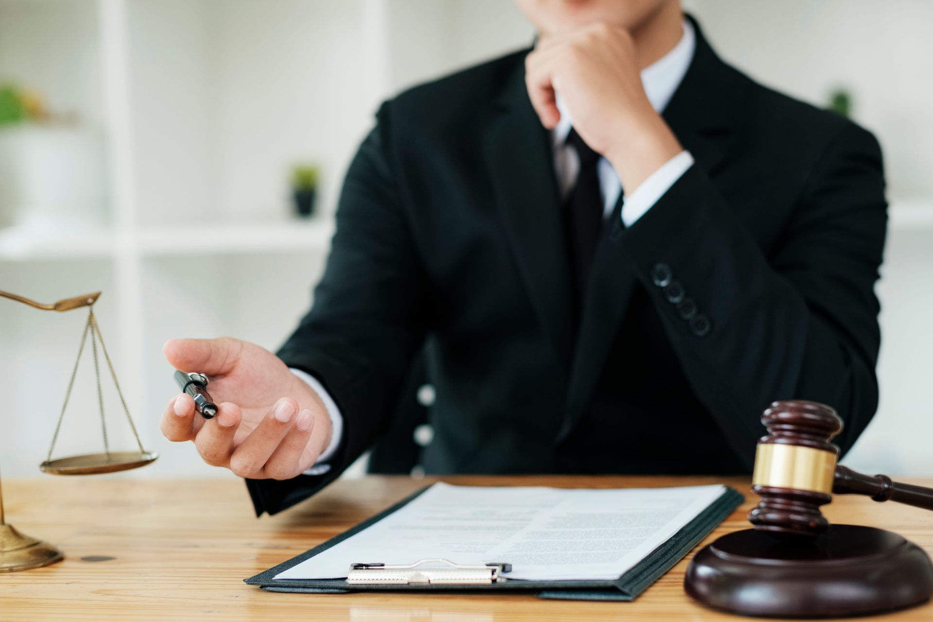 Lawyer with gavel and scales at desk reviewing documents in office