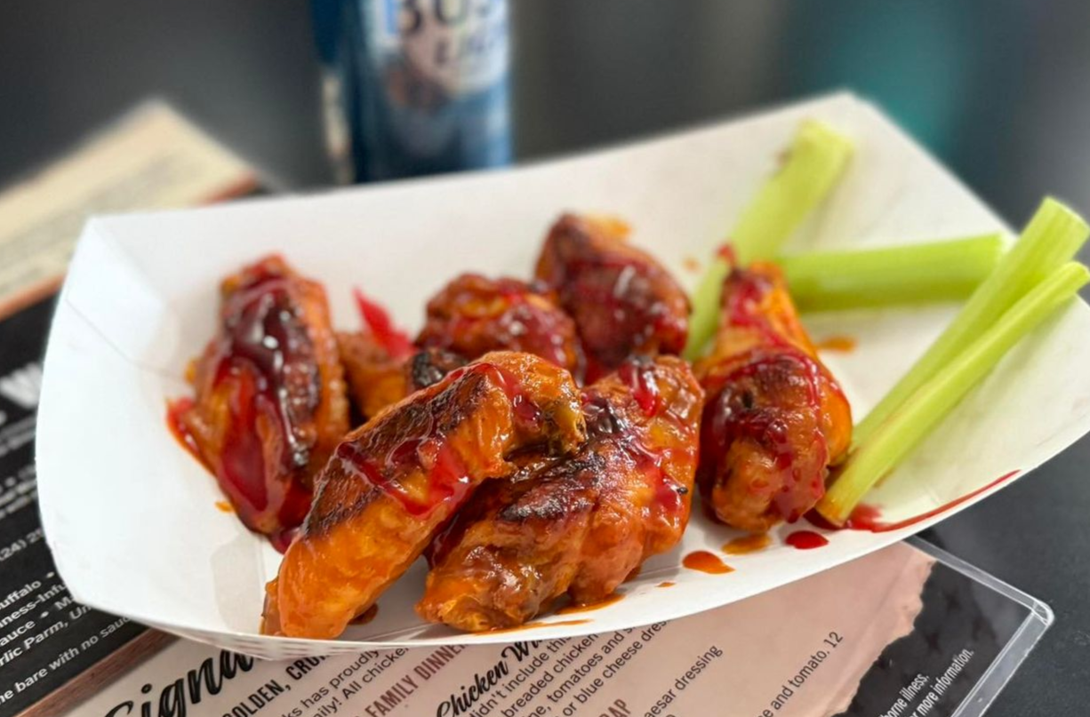 Buffalo chicken wings with celery sticks on a tray, glazed with sauce