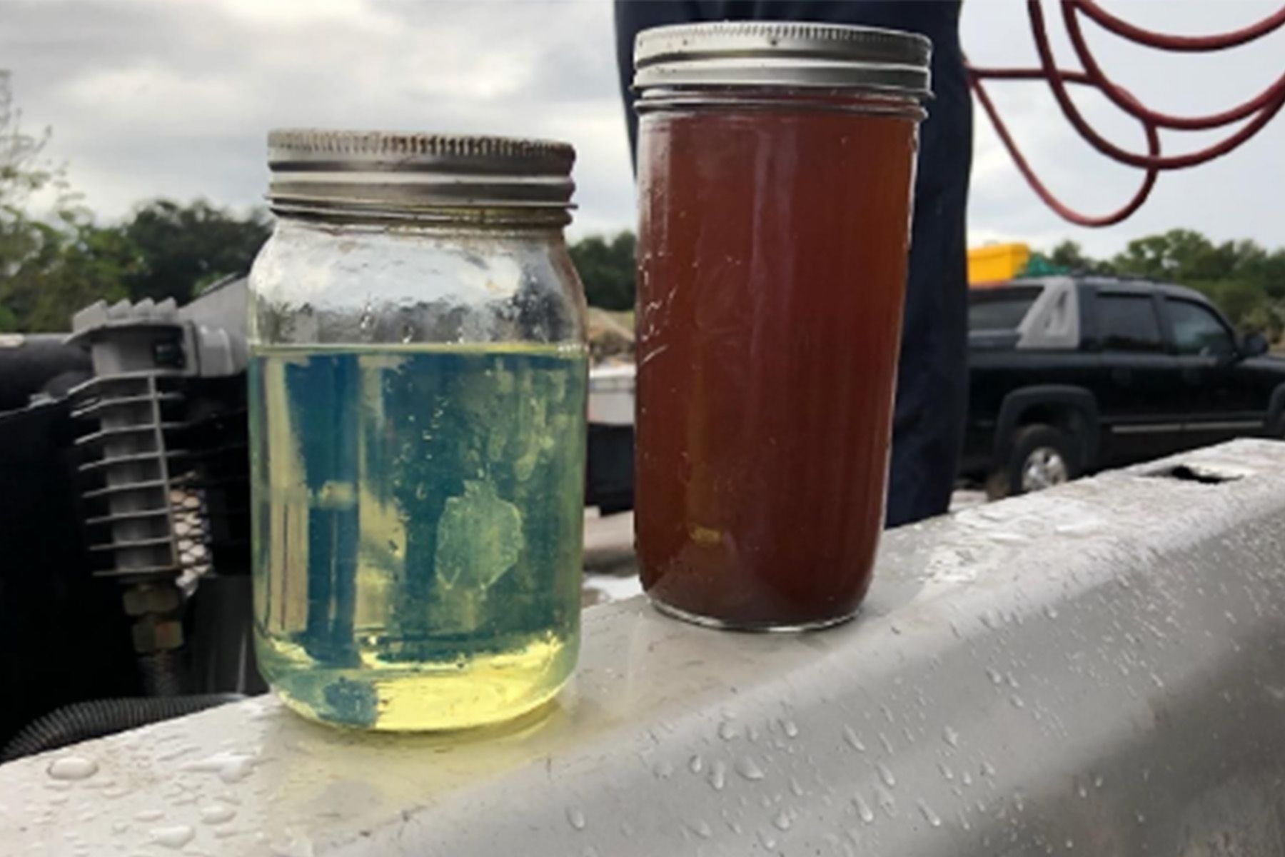 Two jars of different colored liquids are sitting on a table.