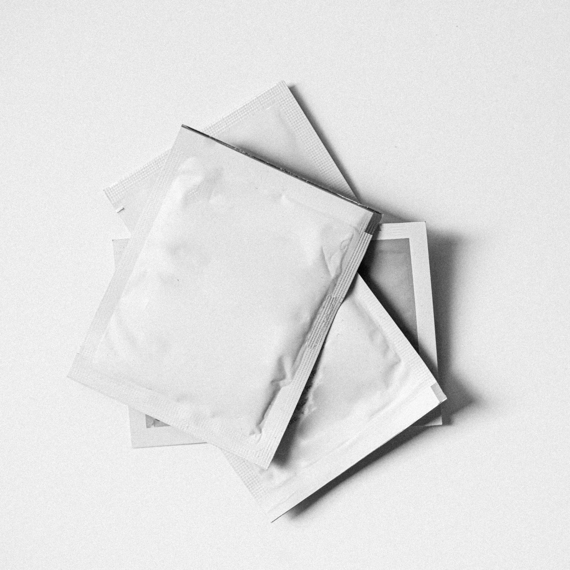 Three white envelopes are stacked on top of each other on a white surface.