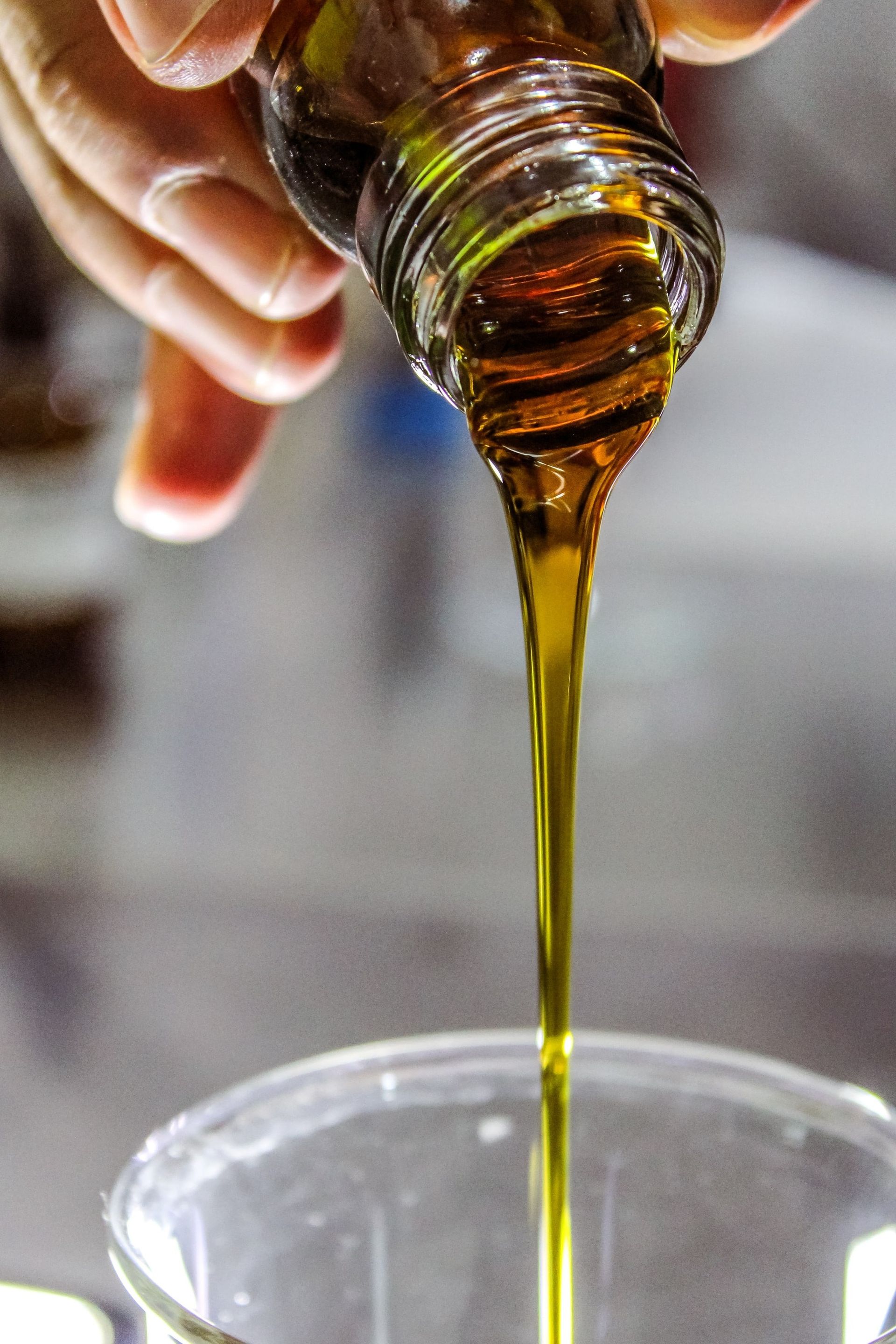 A person is pouring oil from a bottle into a cup.