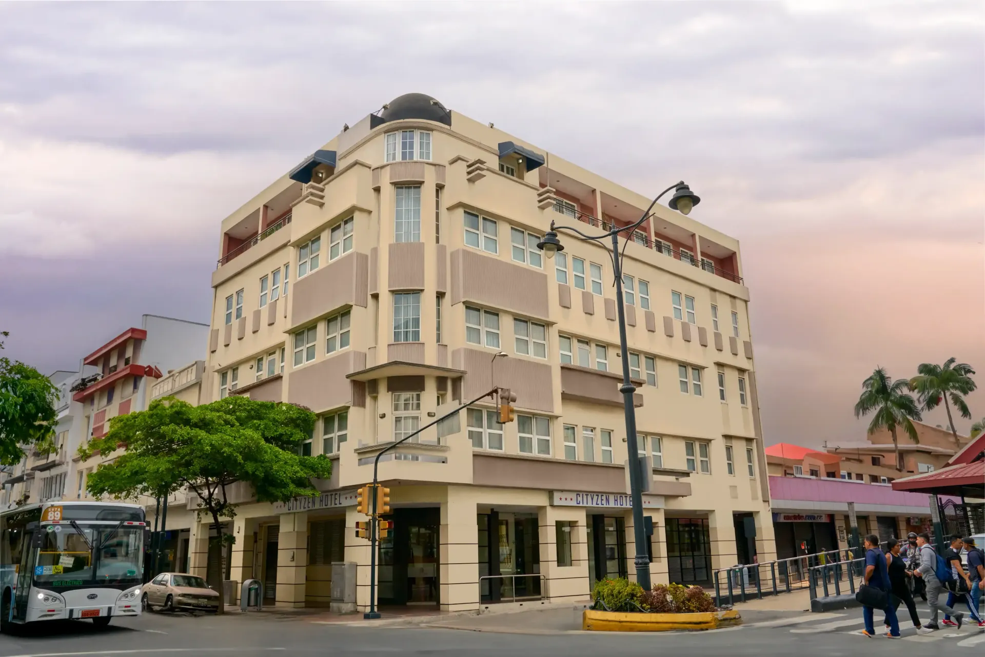 A large building with a lot of windows is on the corner of a city street.